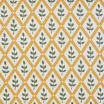 Detail of fabric in a lattice and leaf print in green and yellow on a white field.