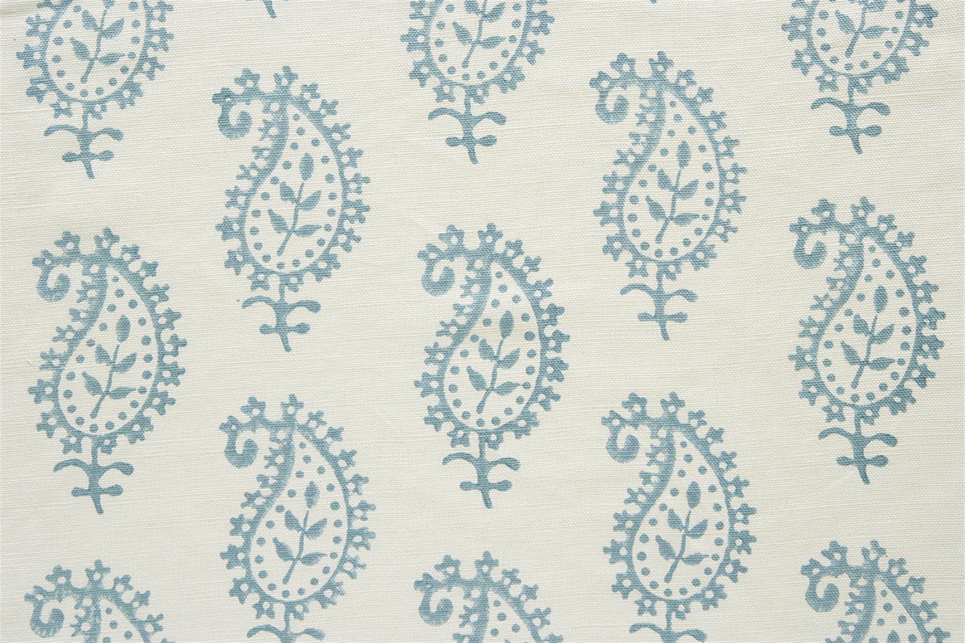 Detail of fabric in a repeating paisley print in light blue on a cream field.