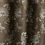 Draped printed fabric in a floral and dot pattern in beige and white on a brown field.