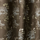 Draped printed fabric in a floral and dot pattern in beige and white on a brown field.