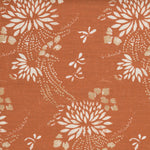 Detail of a linen fabric in a floral and dot pattern in white and gold on a rust field.