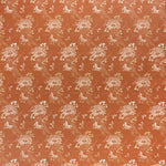 printed linen fabric in a floral and dot pattern in white and gold on a rust field.