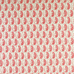 Detail of fabric in a repeating leaf print in pink and red on a cream field.