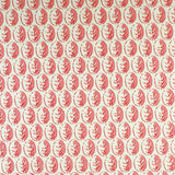 Detail of fabric in a repeating leaf print in pink and red on a cream field.