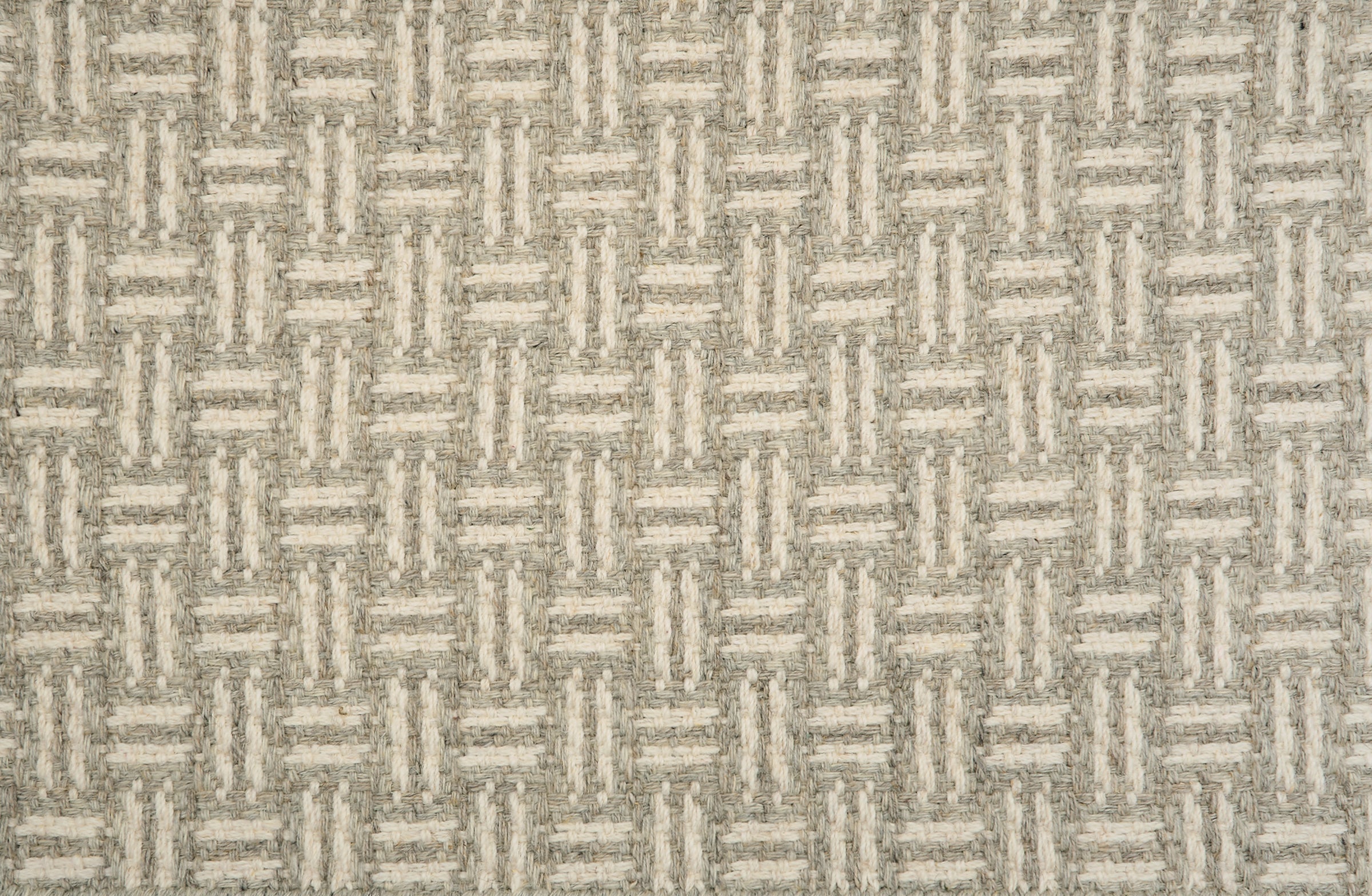 Broadloom carpet with a geometric herringbone design in cream and grey.