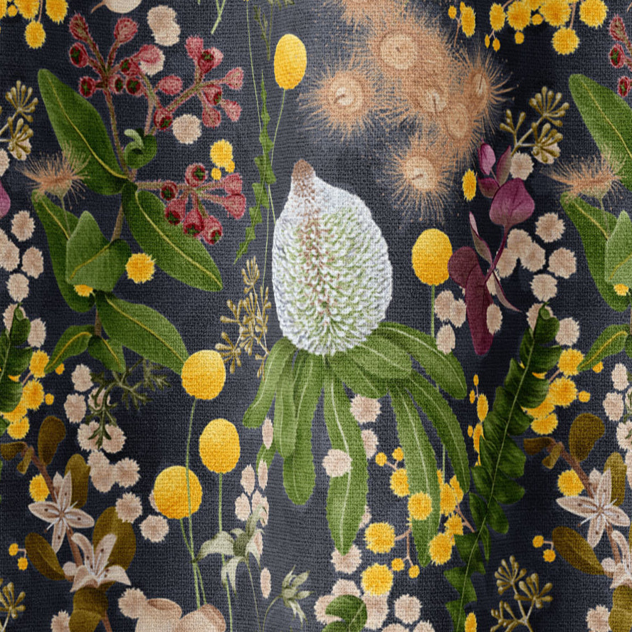 Draped fabric in a large-scale botanical print in shades of pink, yellow and green on a navy field.
