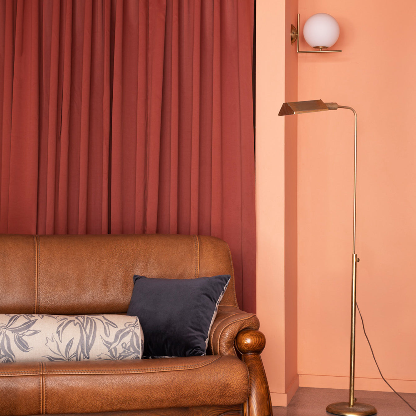 Modernist living room in orange and red tones with a leather couch and gray and cream throw pillows.