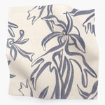Square fabric swatch in a painterly leaf print in blue-gray on a cream field.