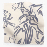 Square fabric swatch in a painterly leaf print in blue-gray on a cream field.