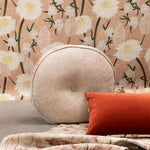 A tableau of arranged throw pillows and fabric yardage in tan, red and various floral prints.