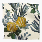 Square fabric swatch in a photorealistic floral print in shades of yellow, white and green on a cream field.