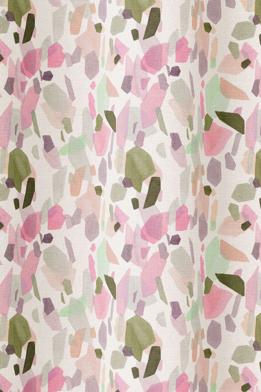 Draped fabric in an abstract shape print in shades of pink, purple and green on a cream field.