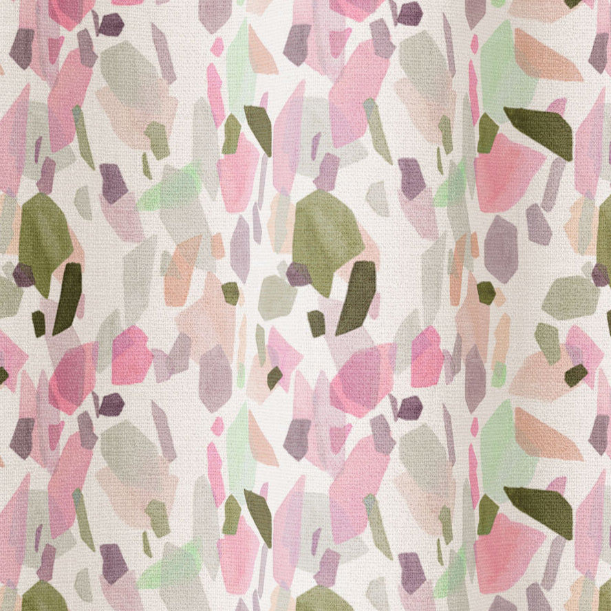 Draped fabric in an abstract shape print in shades of pink, purple and green on a cream field.