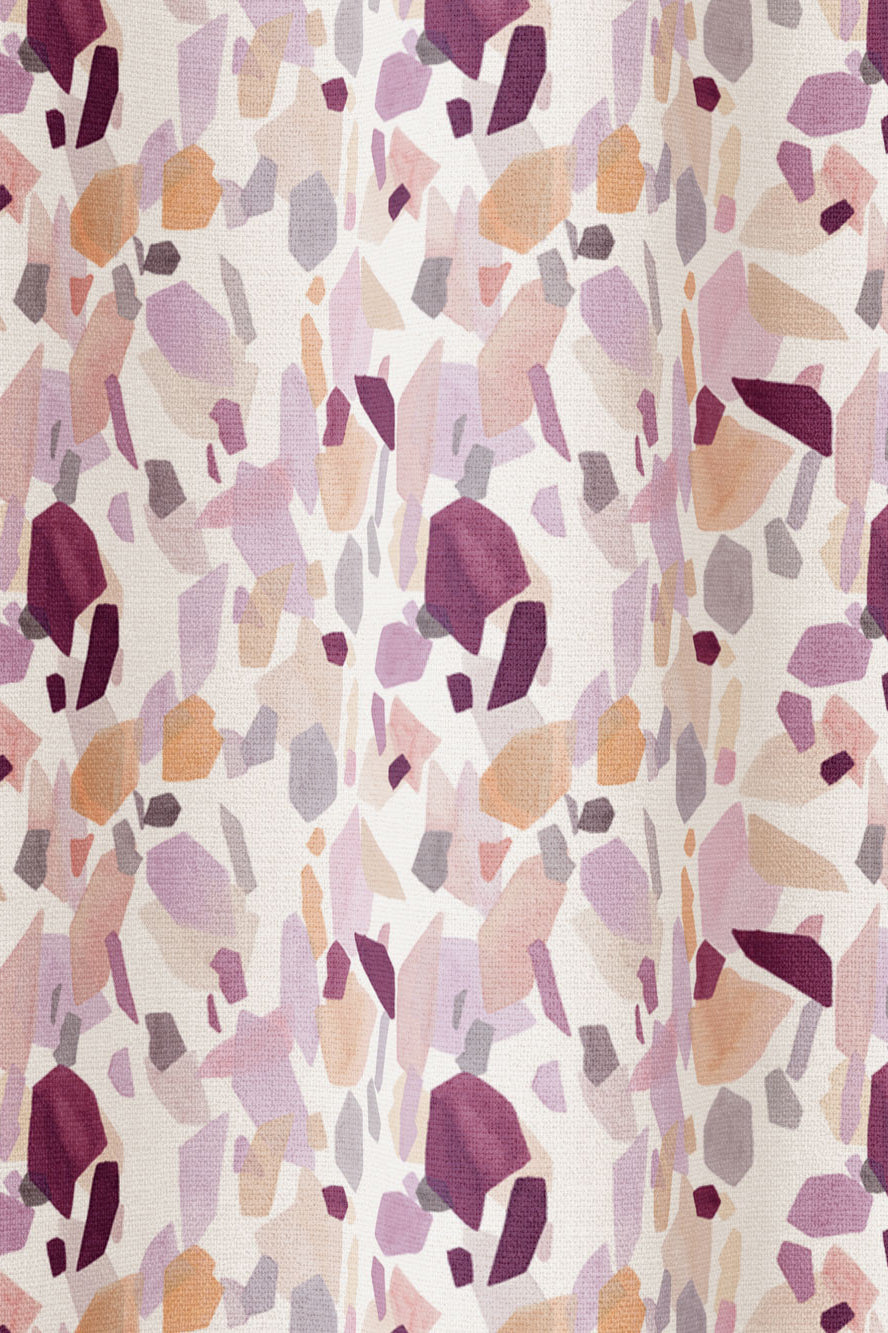 Draped fabric in an abstract shape print in shades of purple, maroon and orange on a cream field.