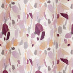 Draped fabric in an abstract shape print in shades of purple, maroon and orange on a cream field.