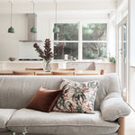 Modernist living and dining space with a gray couch topped with a throw pillow in a photorealistic floral print.