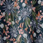 Draped fabric in a large-scale botanical print in shades of blue, green and coral on a navy field.