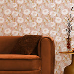 A couch and end table stand in front of a wall papered in a playful floral print in pink, white and tan.