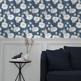 A couch and end table stand in front of a wall papered in a playful floral print in white, gray and navy.