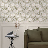 A couch and end table stand in front of a wall papered in a playful floral print in white, olive, gray and cream.