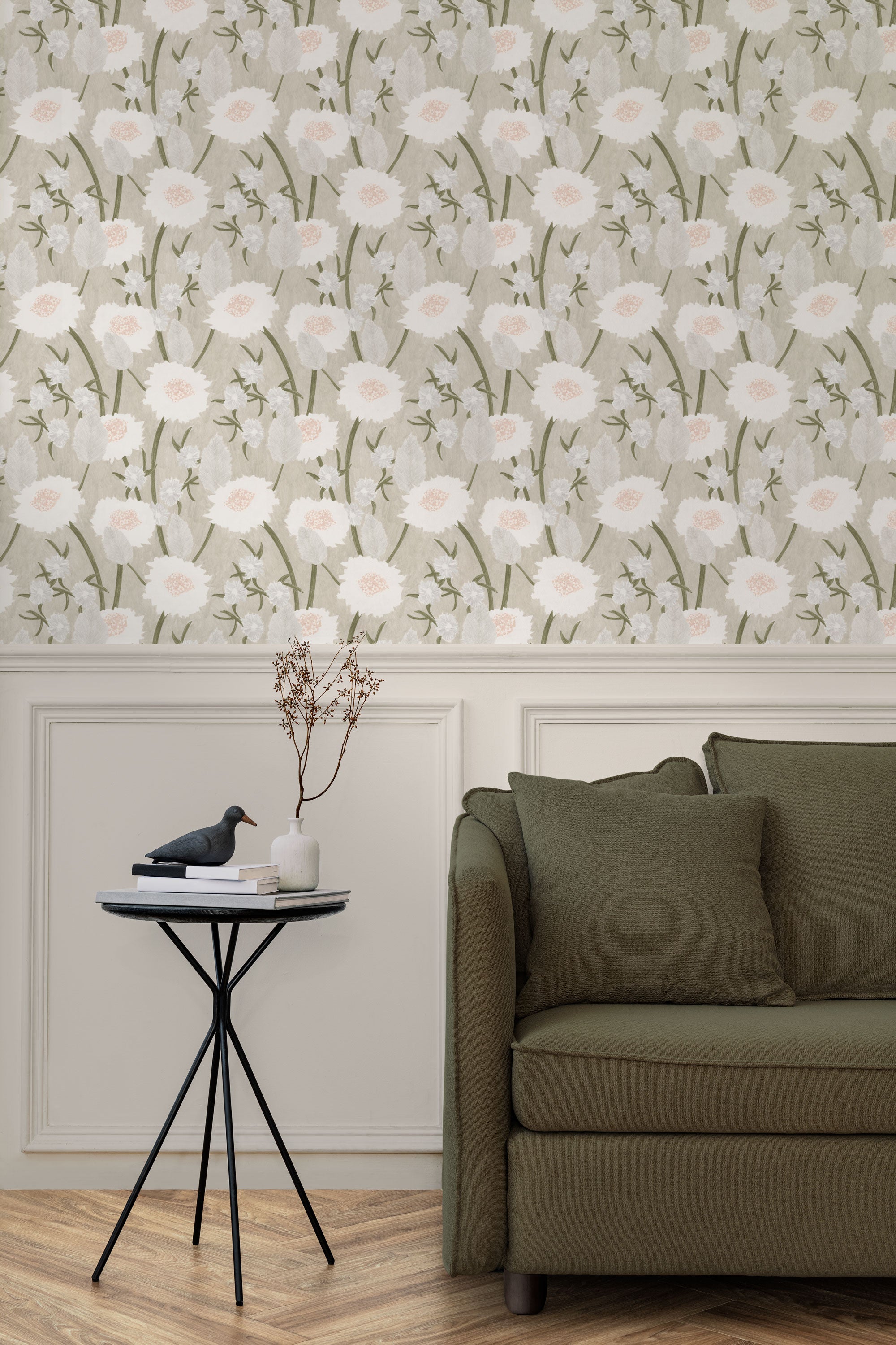 A couch and end table stand in front of a wall papered in a playful floral print in white, olive, gray and cream.