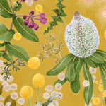 Detail of wallpaper in a large-scale botanical print in shades of pink, yellow and green on a mustard field.