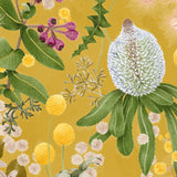 Detail of wallpaper in a large-scale botanical print in shades of pink, yellow and green on a mustard field.