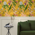 A maximalist living room with a wall papered in a large-scale botanical print in pink, yellow, green and mustard.