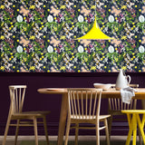 A maximalist dining room with a wall papered in a large-scale botanical print in pink, yellow, green and navy.