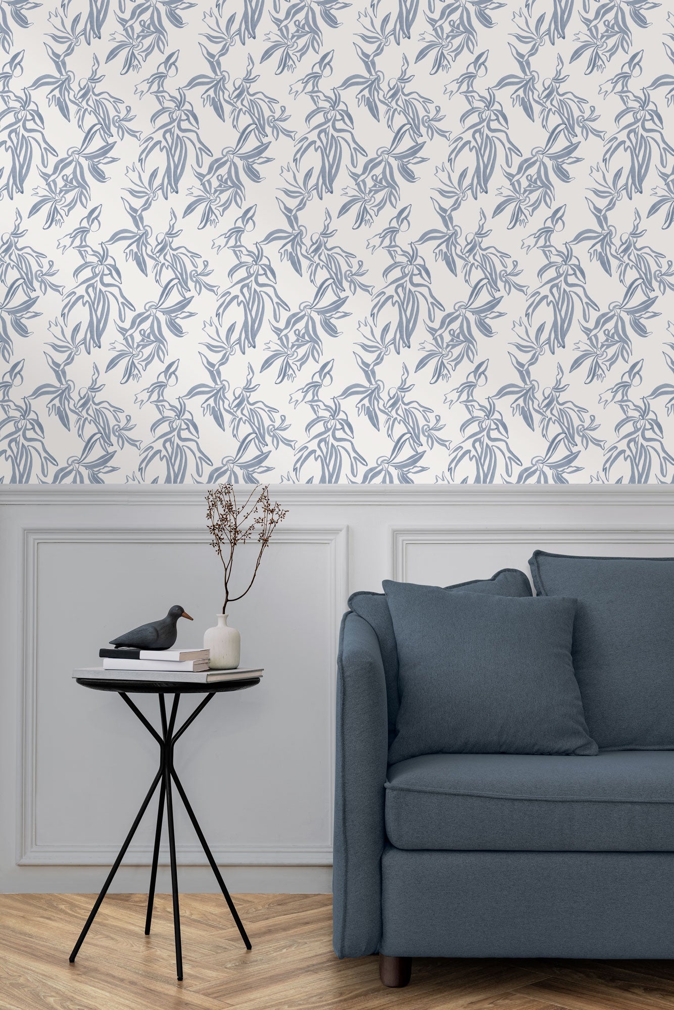 A maximalist living room with a wall papered in a painterly leaf print in blue-gray on a white field.