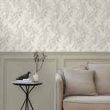 A maximalist living room with a wall papered in a painterly leaf print in cream on a white field.
