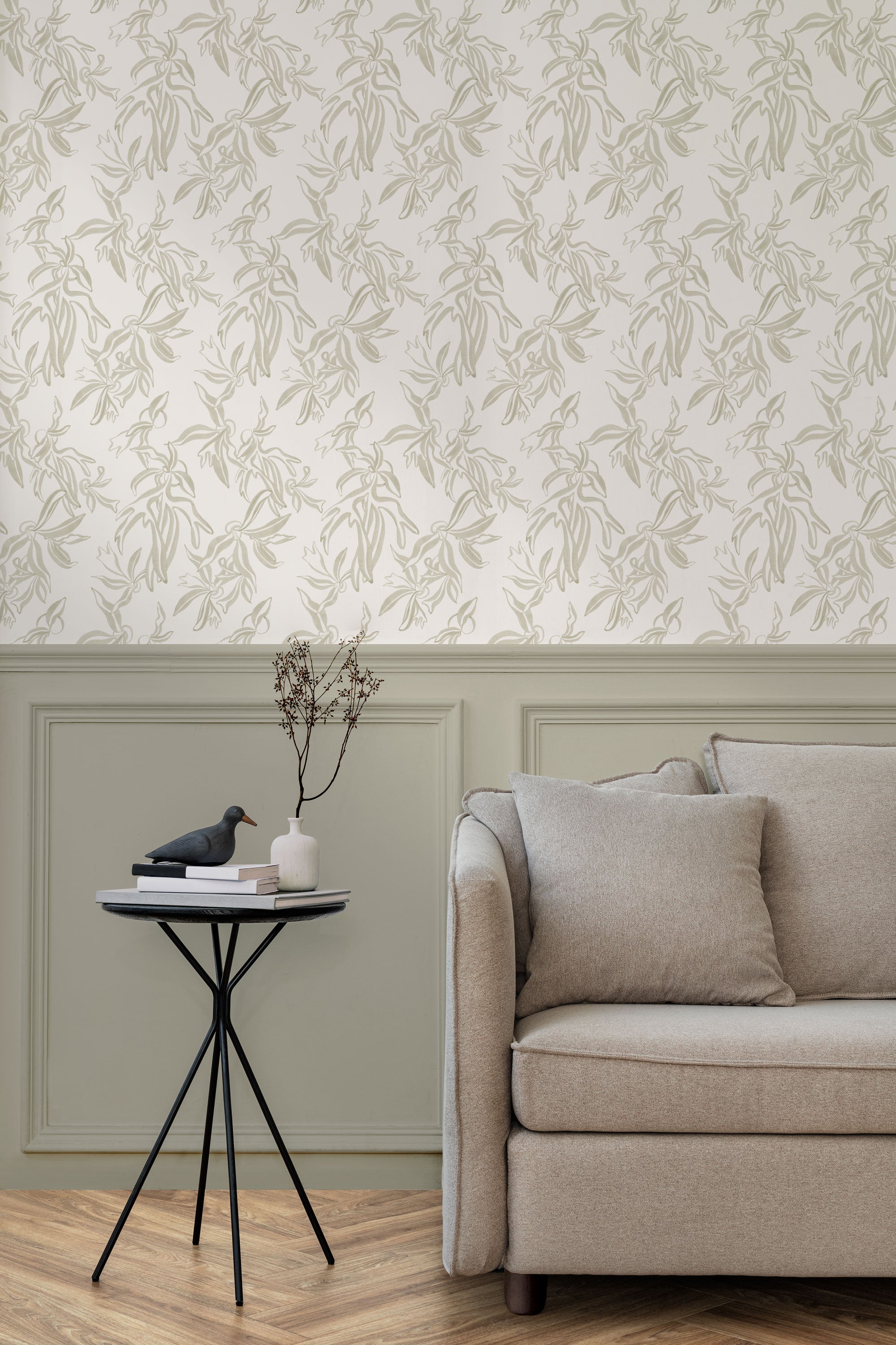 A maximalist living room with a wall papered in a painterly leaf print in cream on a white field.