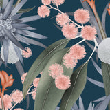 Detail of wallpaper in a large-scale botanical print in shades of blue, green and pink on a navy field.