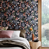 Bedroom with a large window and a wall papered in a large-scale botanical print in shades of blue, green, pink and navy.