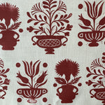 Close-up of fabric in a repeating vase and plant print in rust on a white field.