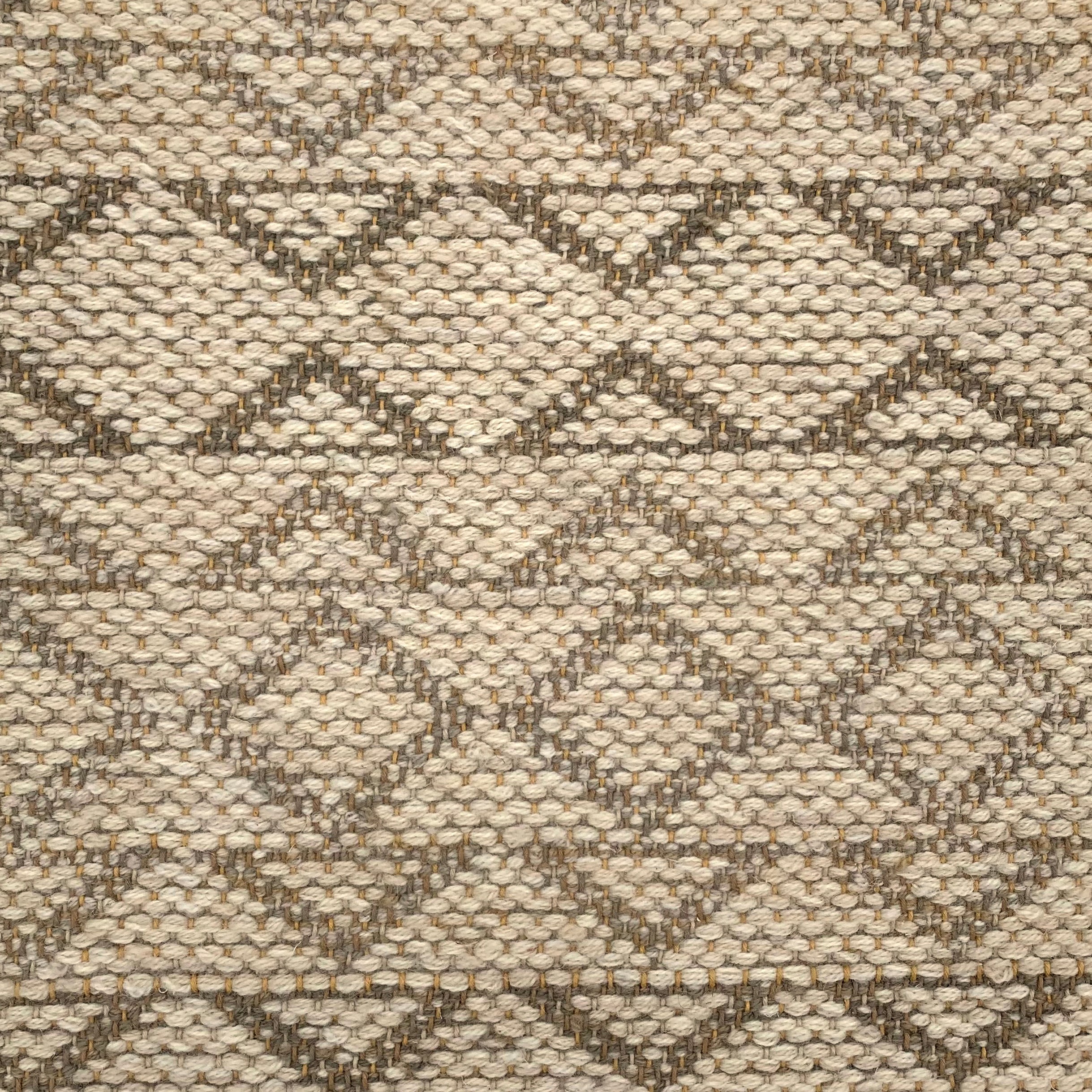 Handwoven rug detail in a geometric design in tan and brown