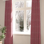 A large, sunny window with long curtains in a playful dot print on a maroon field.