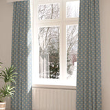 A large, sunny window with long curtains in a playful dot print on a light blue field.