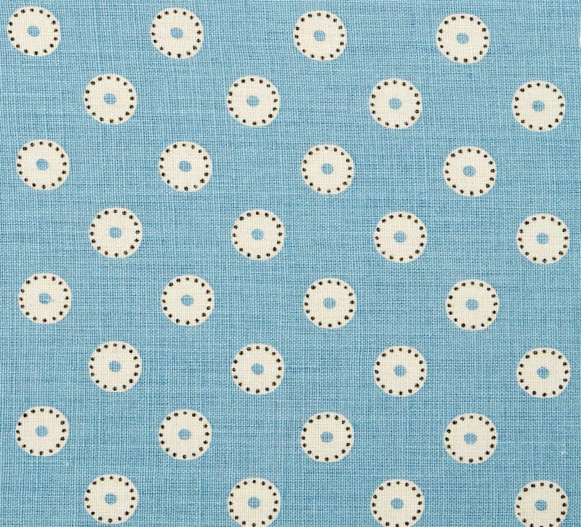 Detail of fabric in a playful dot print in cream and charcoal on a light blue field.