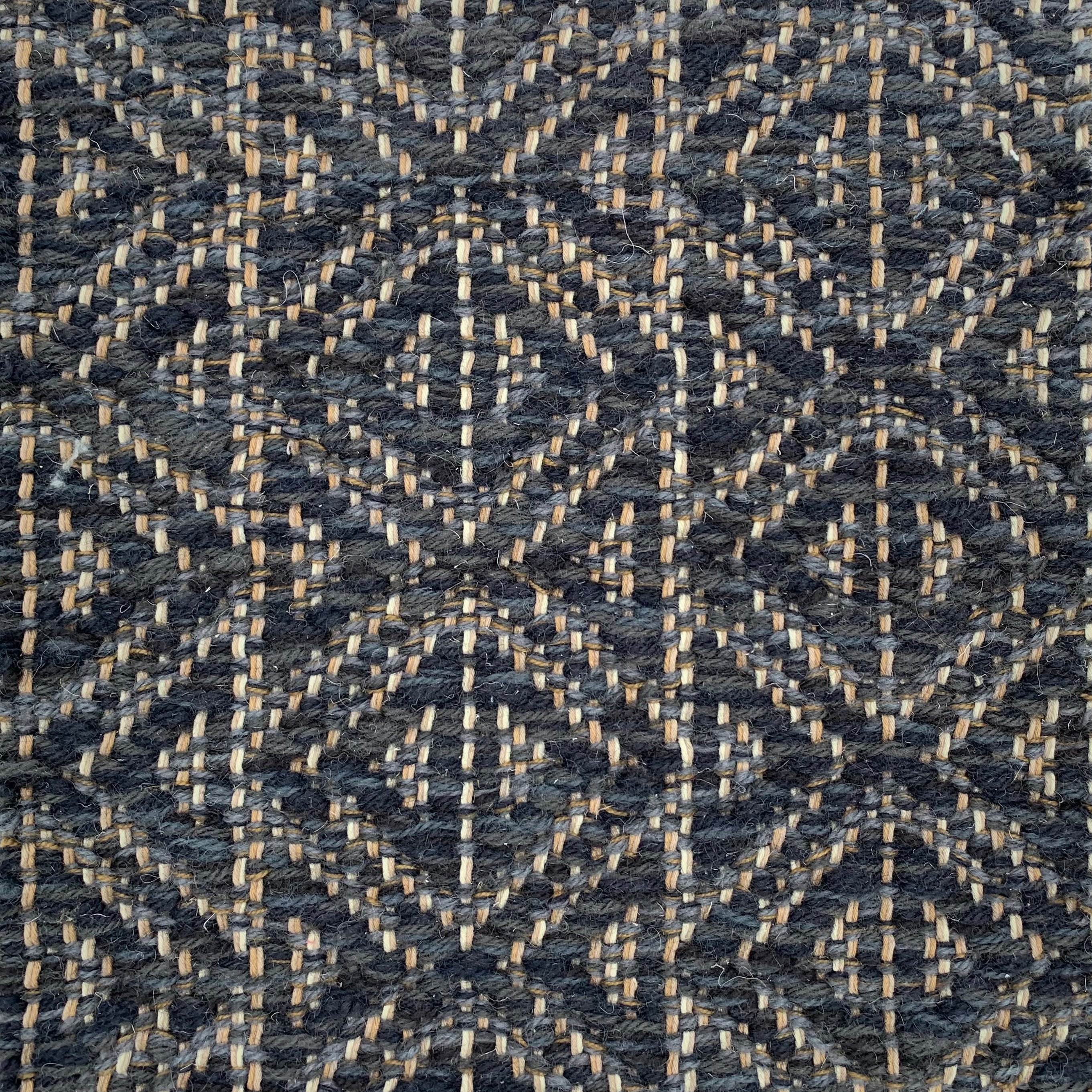 Handwoven rug detail in a diamond design in navy blue and black