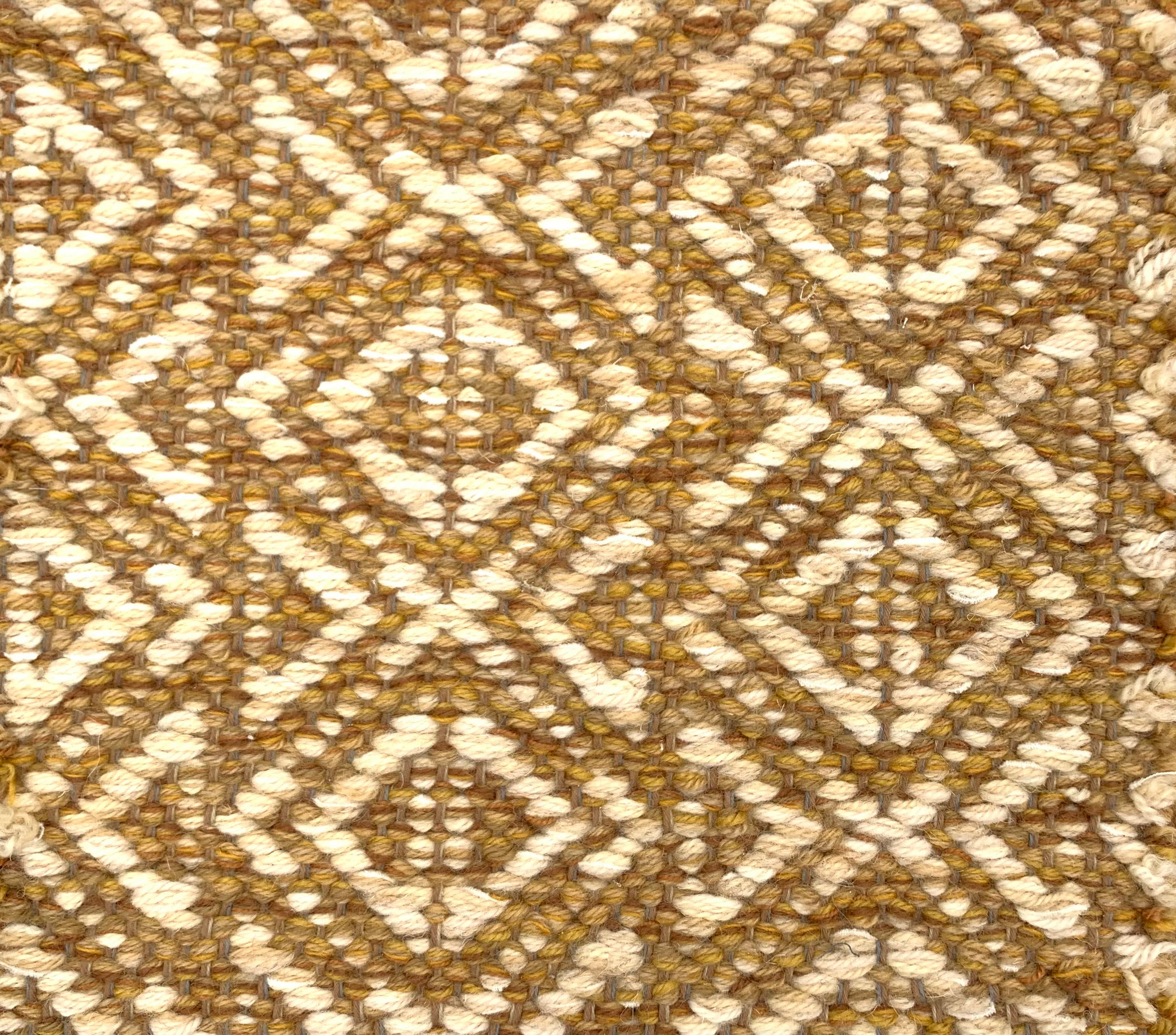 Handwoven rug detail in a diamond design in mustard and beige