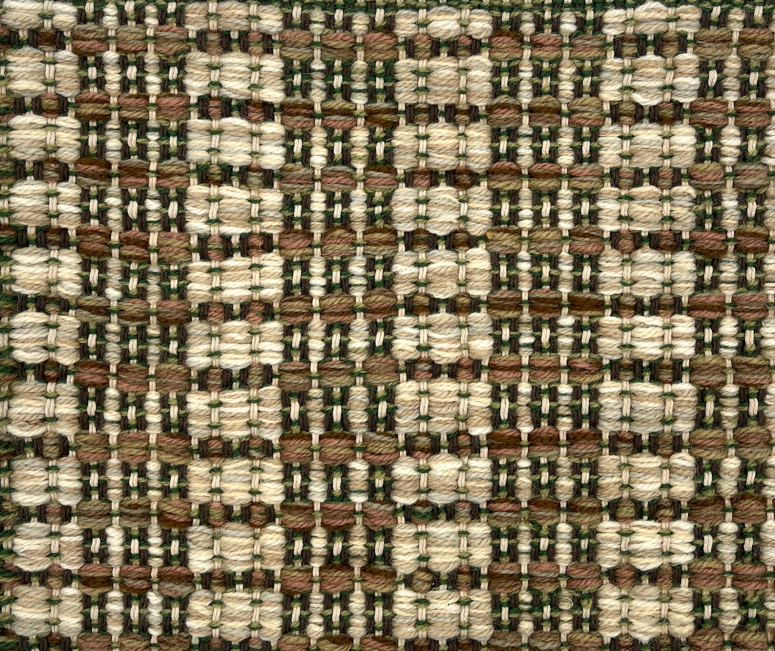 Handwoven rug detail in a checkered design in cream, green and tan