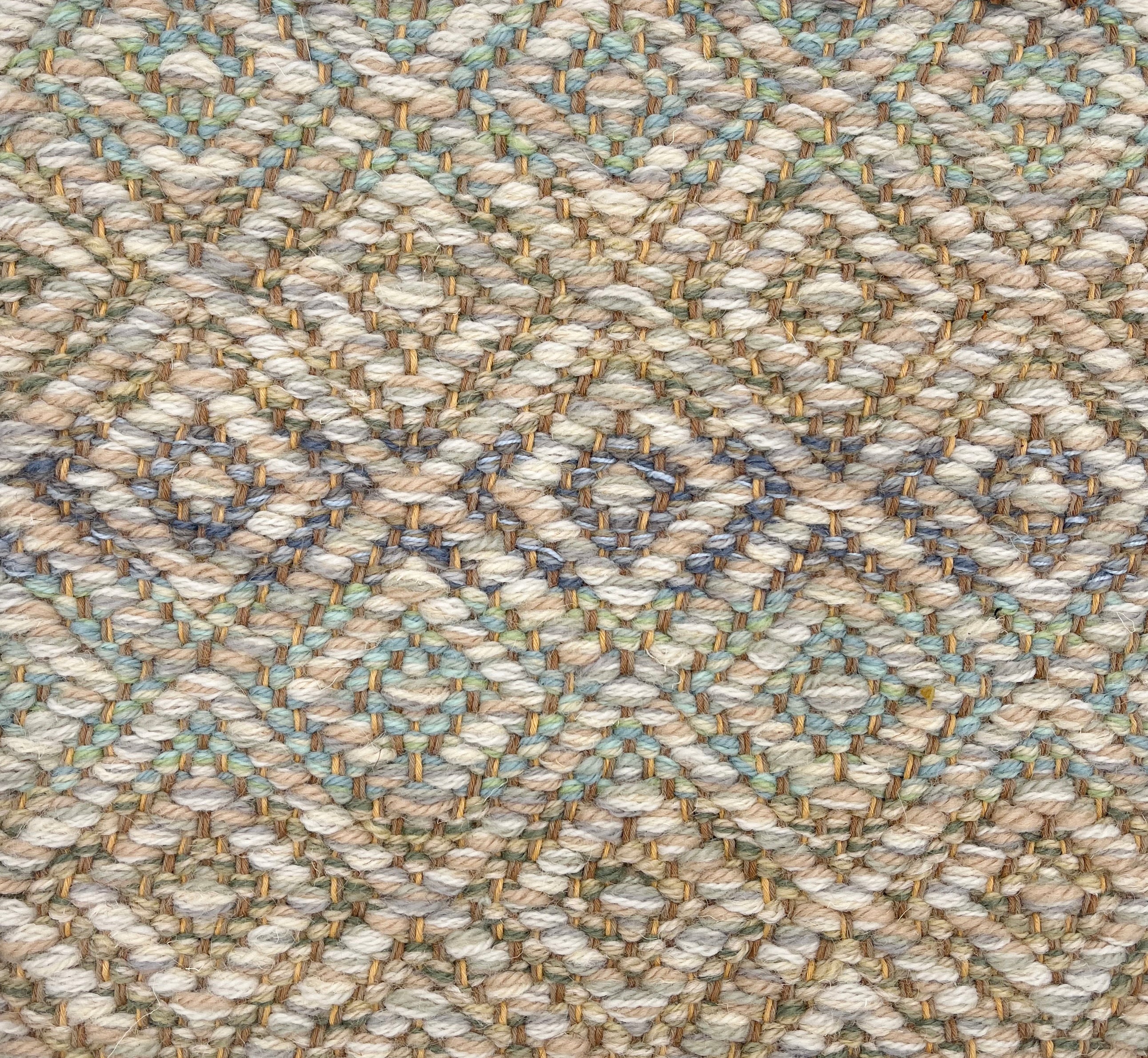 Handwoven rug detail in a diamond design in cream, yellow, blue