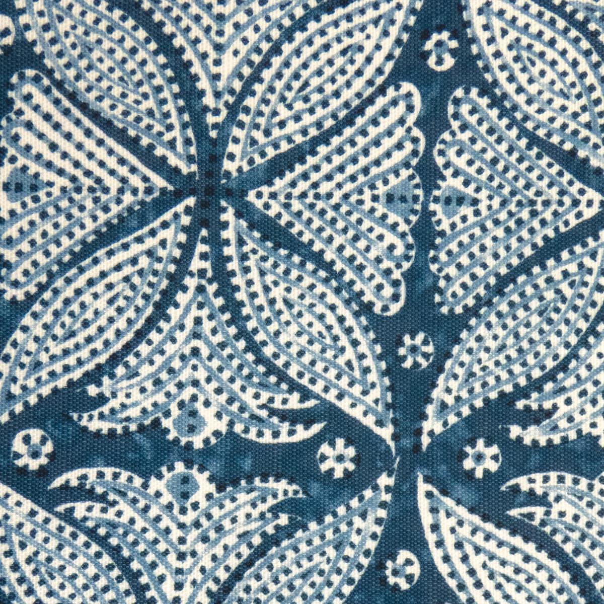 Detail of fabric in a botanical geometric print in shades of blue, cream and navy with a navy dot overlay.