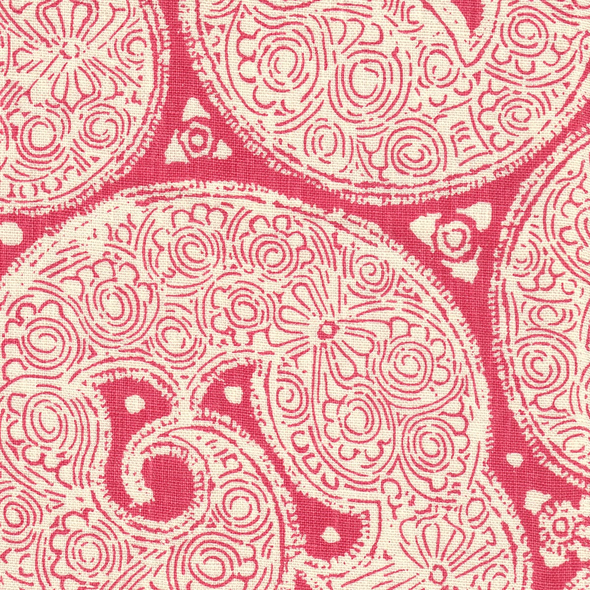 Detail of fabric in a paisley print in cream on a pink field.