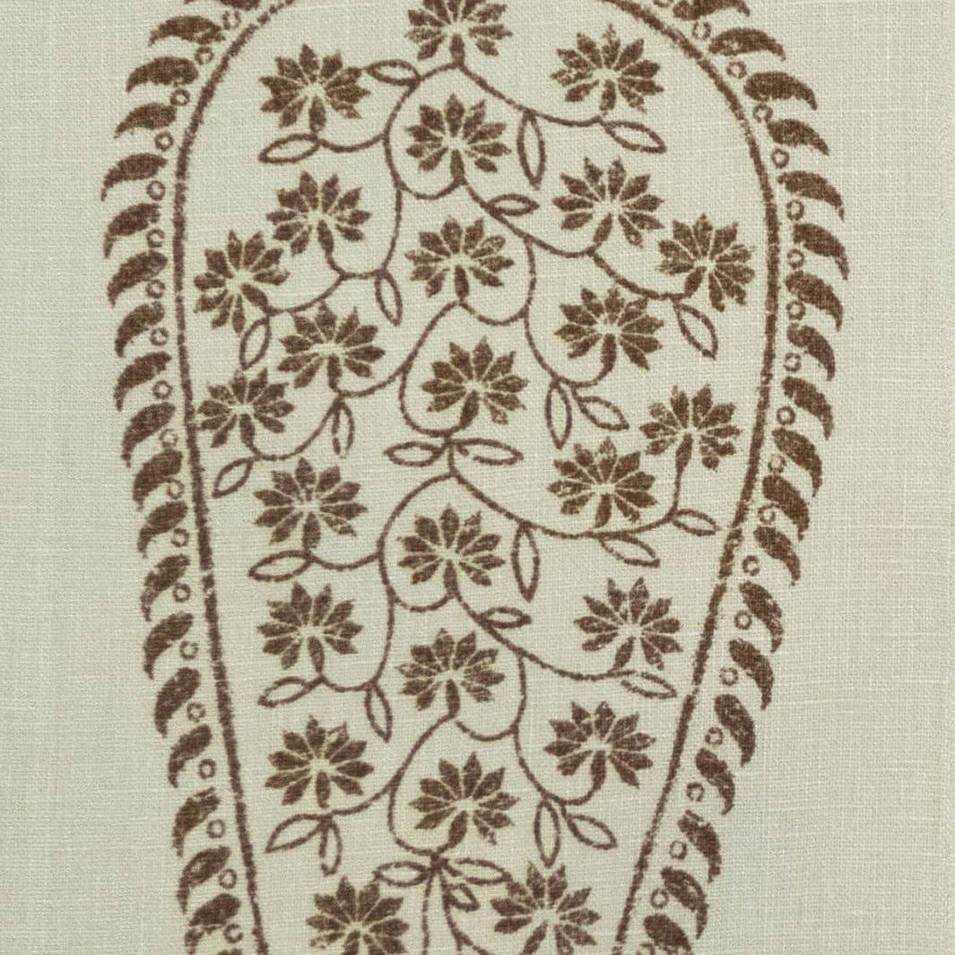 Detail of fabric in an intricate paisley print in brown on a cream field.