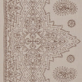 Detail of fabric in a dense paisley border print in brown on a tan field.