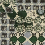 Detail of fabric in a dense curvilinear print in shades of green and gray on a tan field.