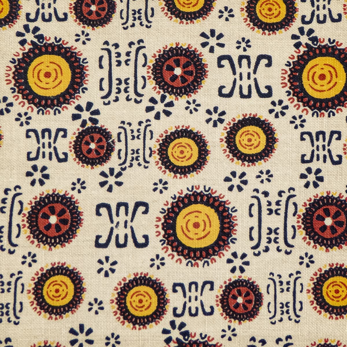 Detail of fabric in a repeating geometric shape print in shades of yellow, red and black on a cream field.