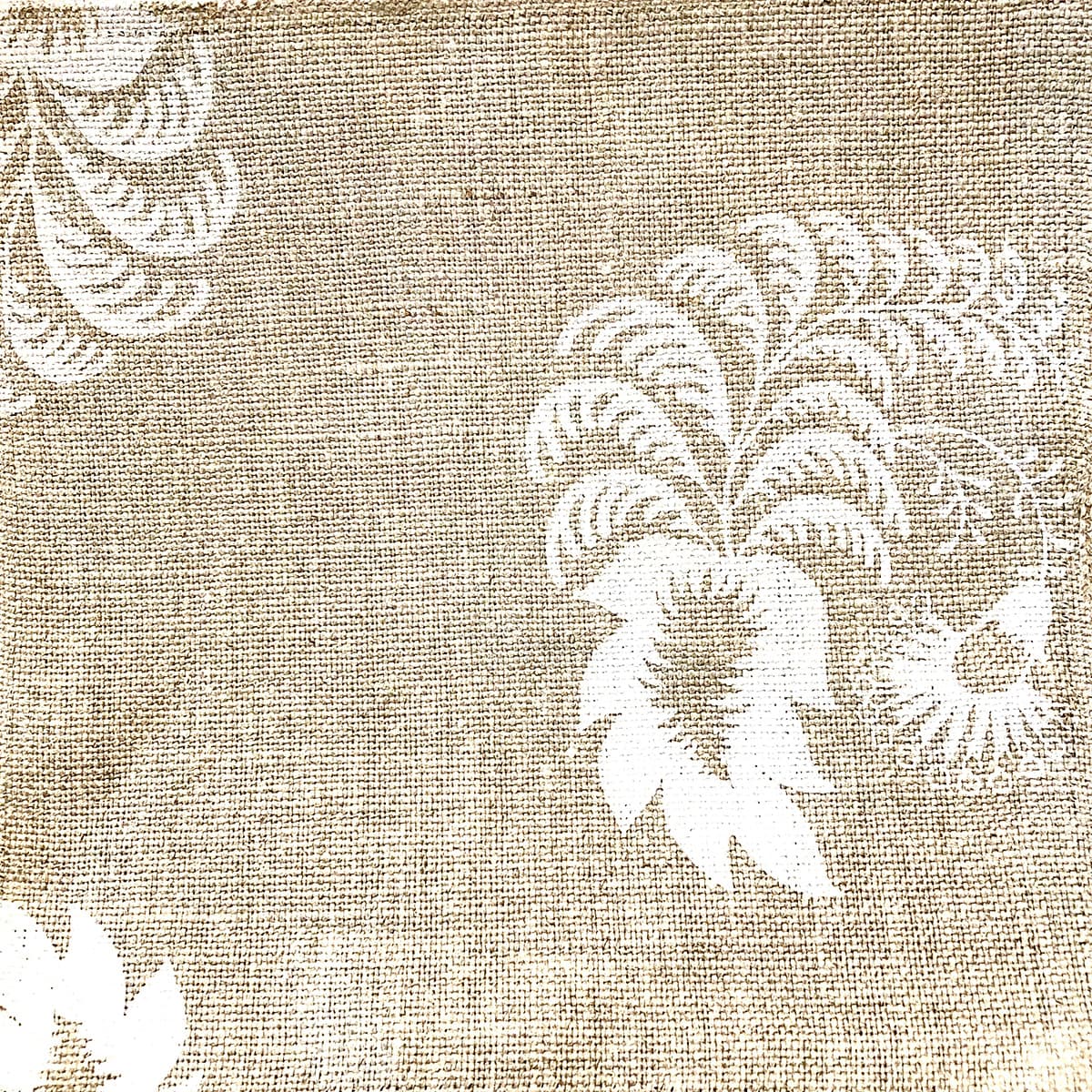 Detail of fabric in a floral paisley print in white on a tan field.